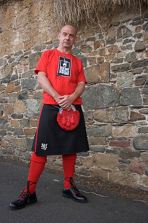 Portrait of guitarist Stevie Lawrence dressed in a kilt and red chilli piper tshirt who plays with the Red Hot Chilli Pipers in Scotland.