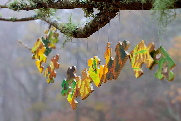 Woodland Art Installation - giant puzzle pieces hanging off a tree branch in a woodland, by Anne Gilchrist at Tombreck Farm, Lawers, Loch Tayside (Perthshire, Scotland).