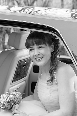 Black and white photo of a bride holding her bridal bouquet sitting in the bridal car.