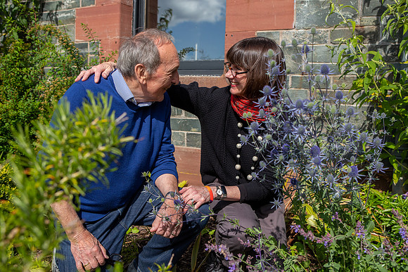 Husband and wife looking at each other crouched down in a garden outside the exclusive holiday home Dun Aluinn in Aberfeldy, Perthshire, Scotland.