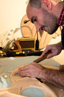 A luthier using a chisel on the back of a half-built guitar.