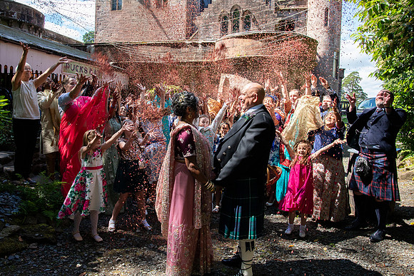 An Indian bride and Scottish groom celebrate their wedding with friends and family throwing confetti at Culdees Castle near Muthill.